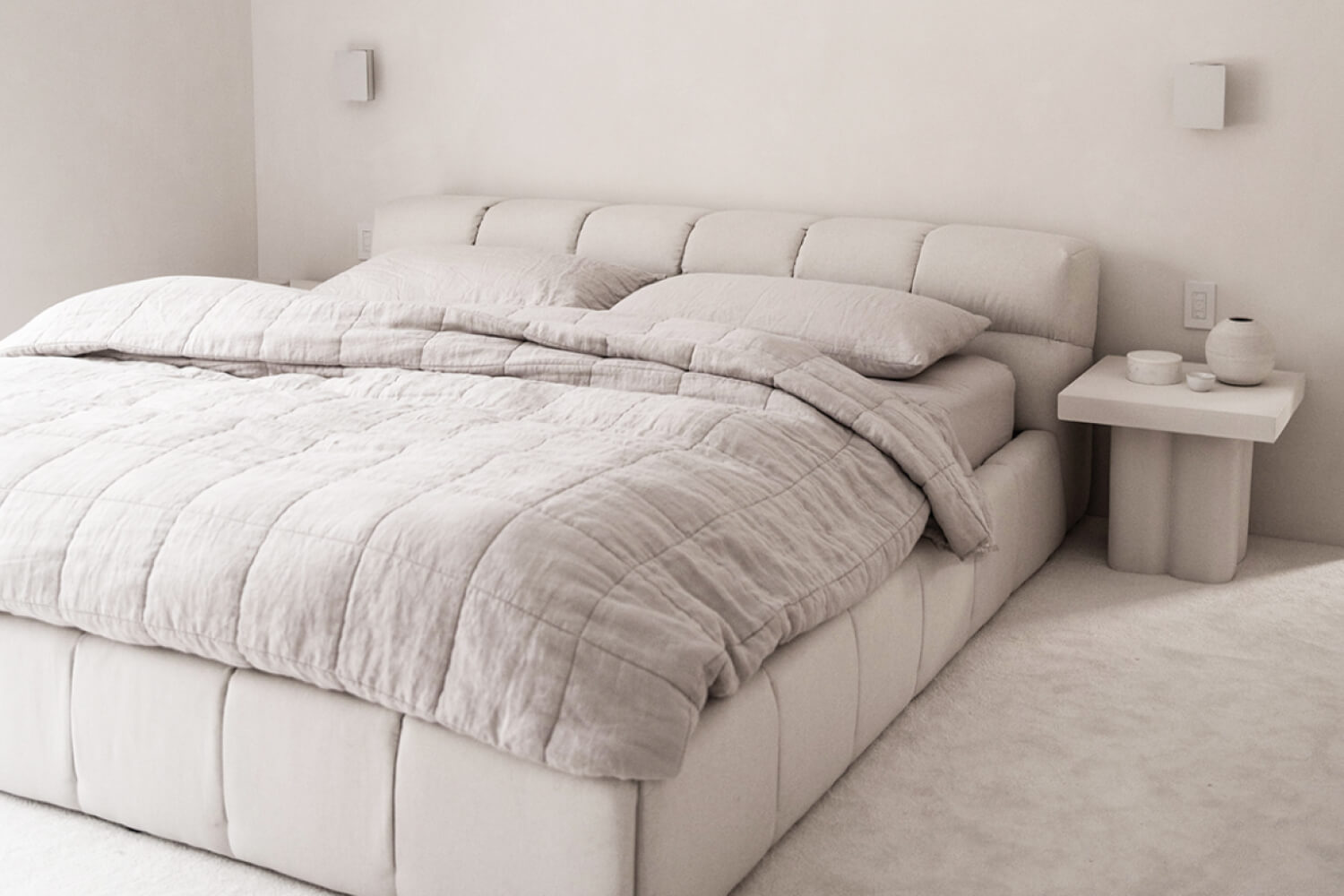 Minimalist bedroom featuring a Tufted bed with a plush headboard and a matching duvet. 