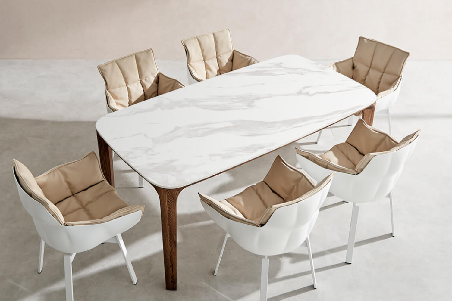 The Myko Modern Rectangular Ceramic Dining Table, surrounded by white chairs with beige cushions, creating a chic and contemporary dining space.
